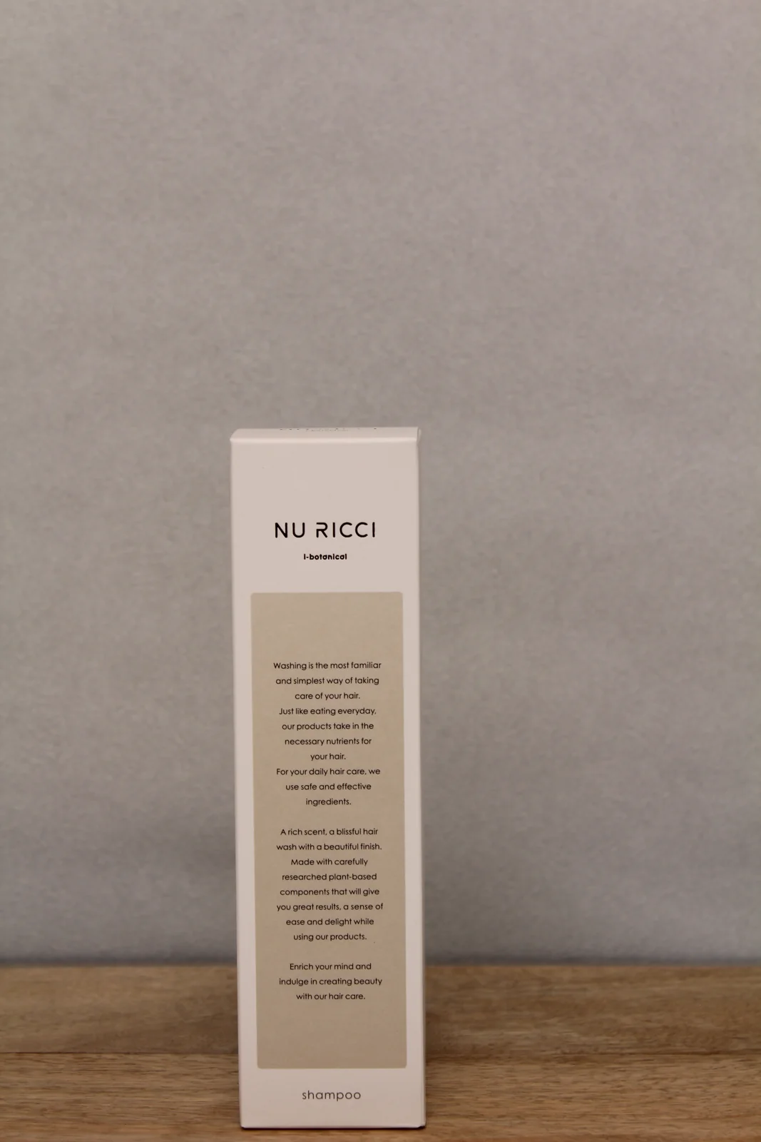 木の台に置かれたNU RICCIシャンプーの箱